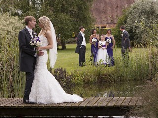 Bride and groom on the bridge over a garden pond.